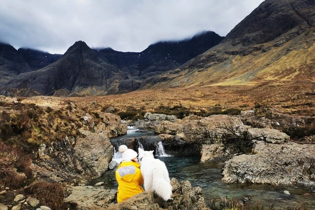 Un chien et son maître devant un rivière lors d'un voyage en Écosse